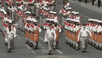 法国阅兵现场，马克龙与第一夫人边看边讨论，其中一方阵人均大胡子，扛着斧头走过